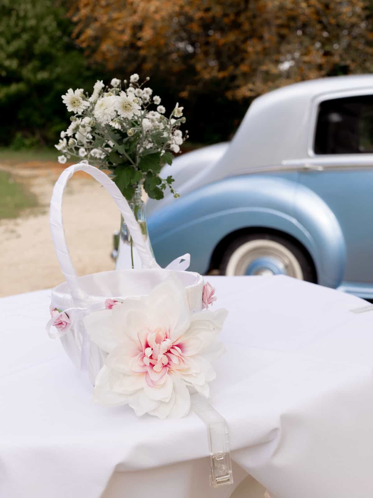 Weißer Blumenkorb mit rosa Dahlien und weißen Rosen vor vintage Hochzeitsauto bei Schloss Kartzow