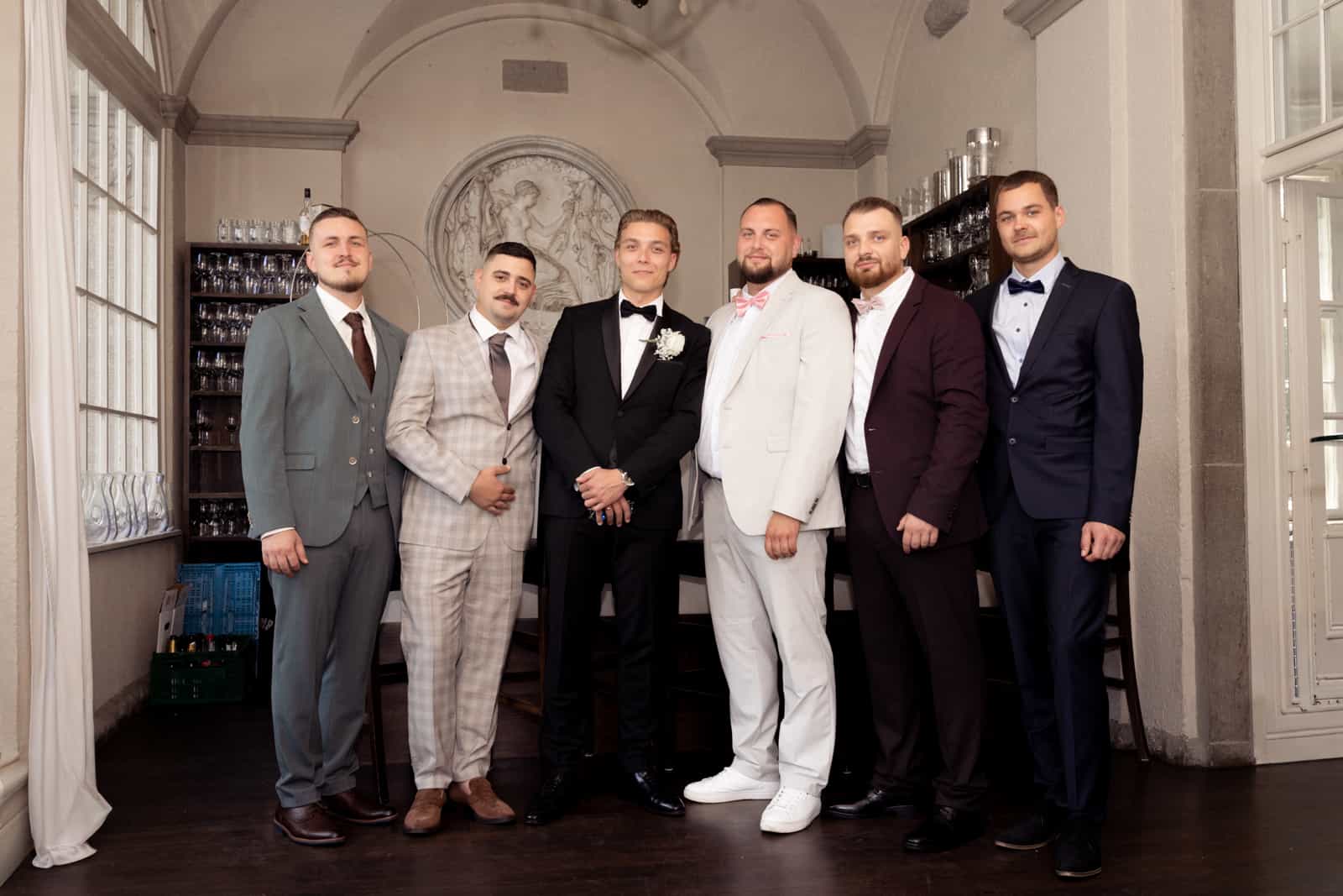 Bräutigam mit fünf Freunden in eleganter Bar mit klassischem Wandrelief