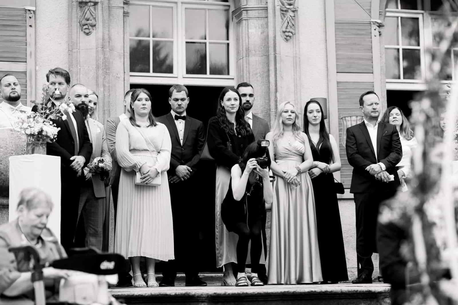 Hochzeitsgäste in formeller Kleidung auf Herrenhaustreppe bei der Zeremonie, Schwarzweiß