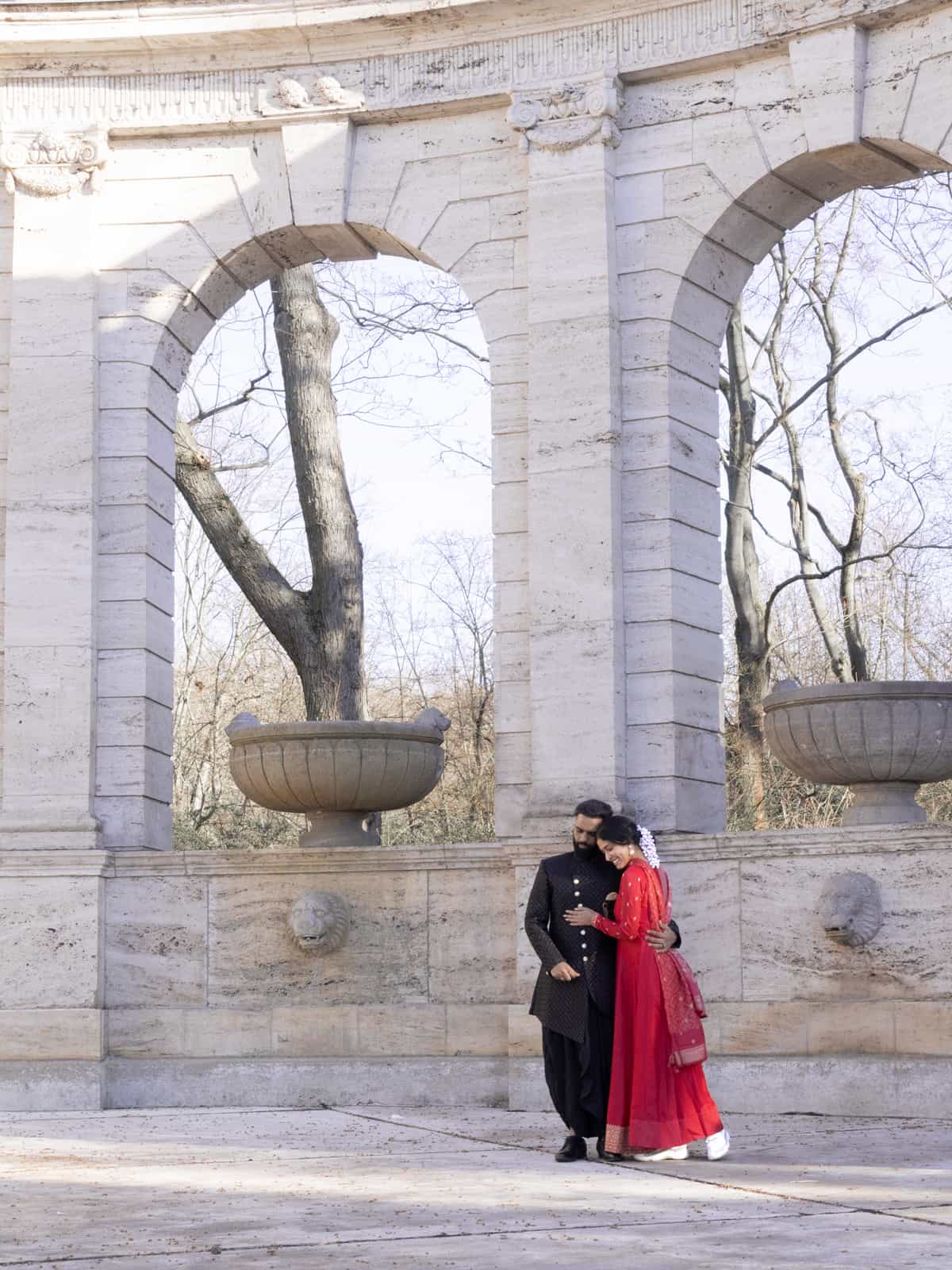 Indisches Brautpaar in traditioneller Hochzeitskleidung vor historischen Steinbögen