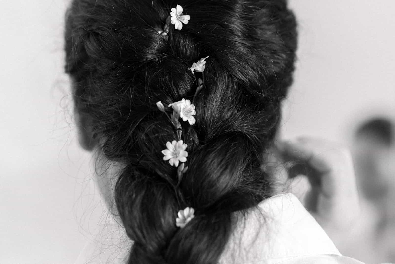 Braided updo hairstyle with white wildflowers woven through, black and white