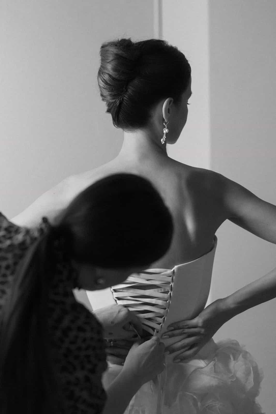 Bride from behind having corset laced, elegant updo hairstyle