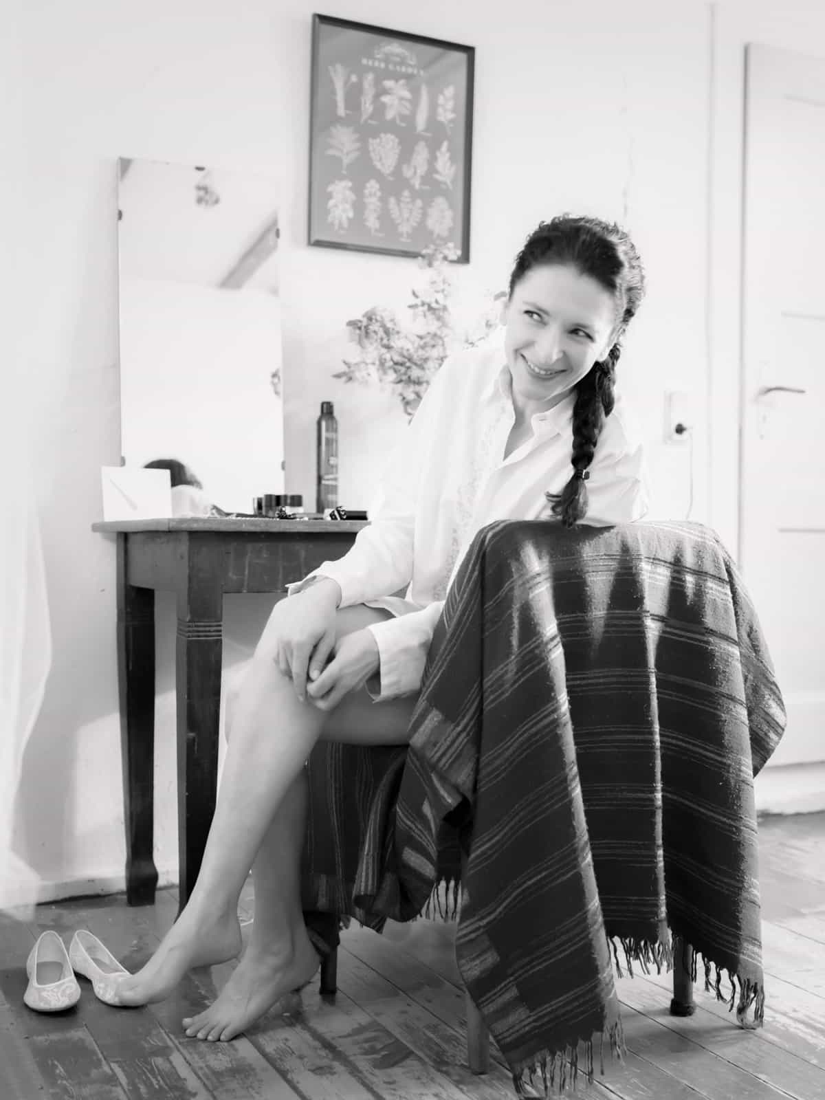 Smiling bride in white silk shirt during wedding preparations