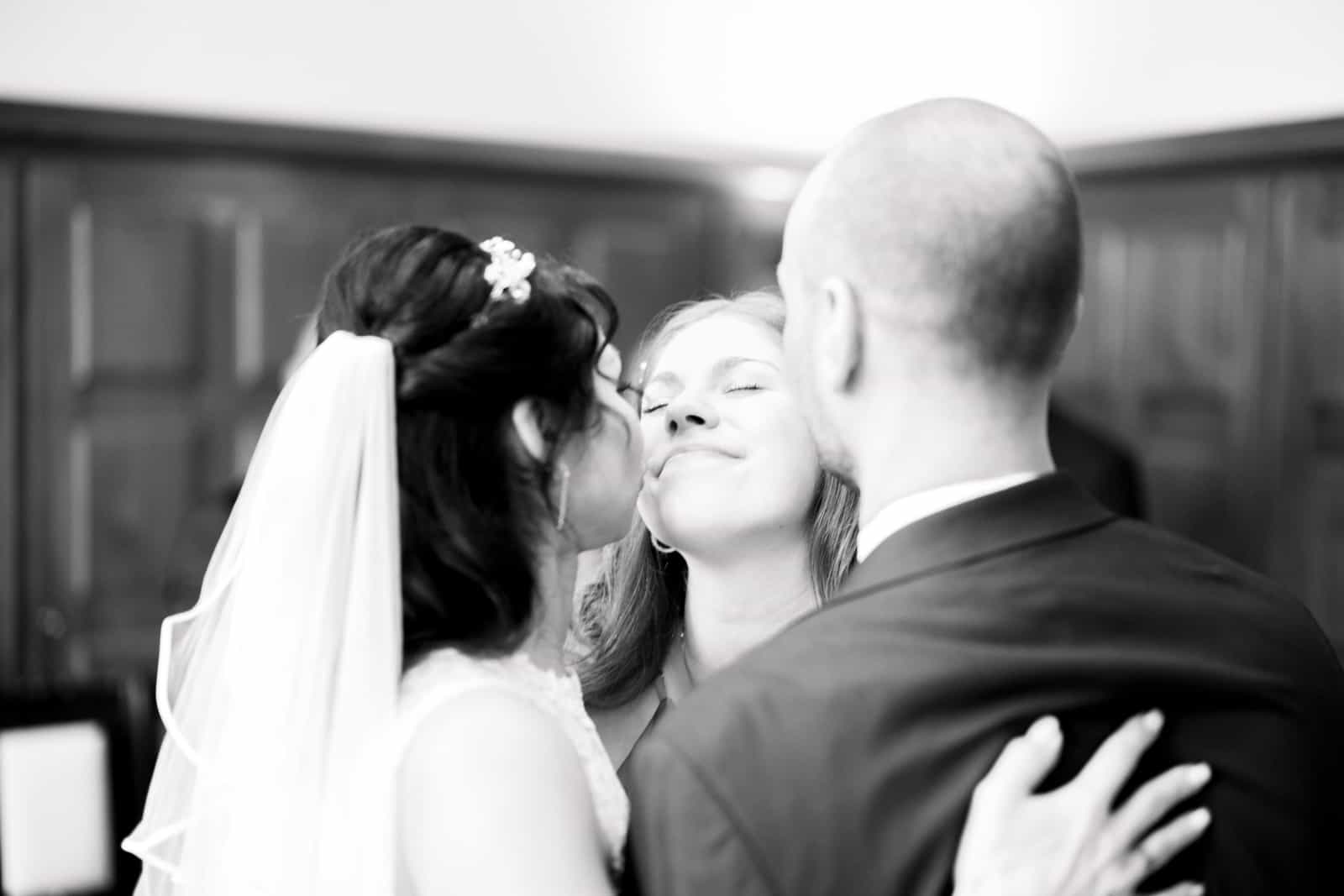 Bride kissing guest on cheek during congratulations, black and white