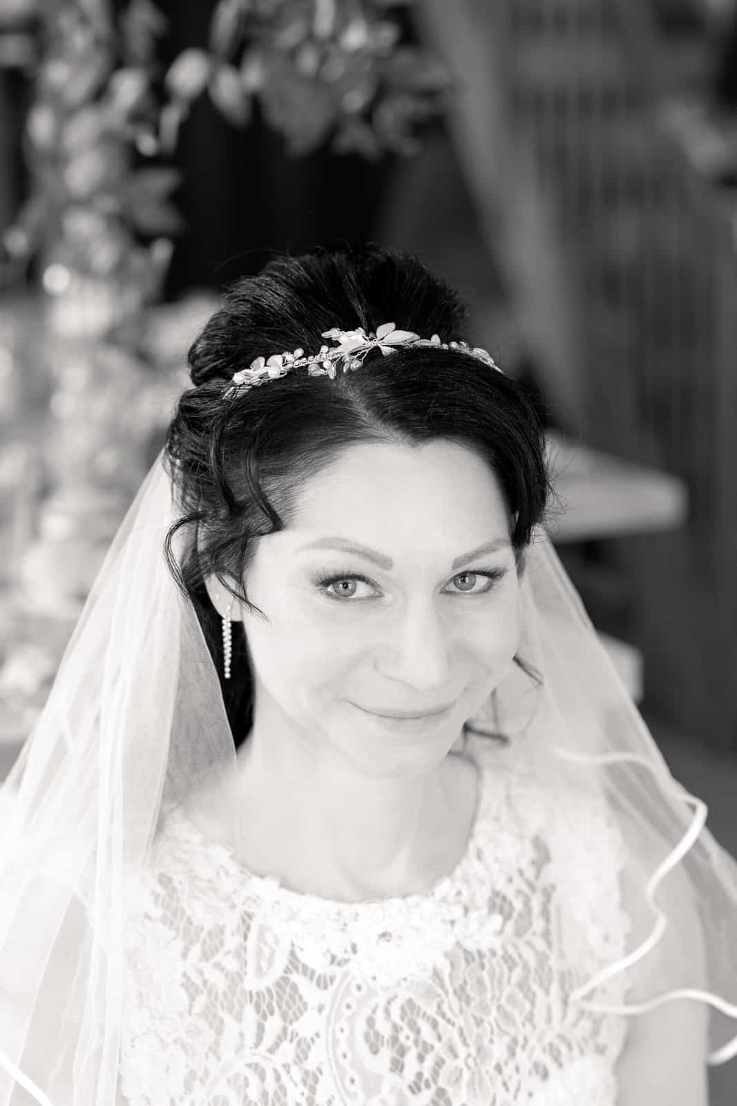 Bride portrait with updo, floral hair accessory and pearl earrings, black and white