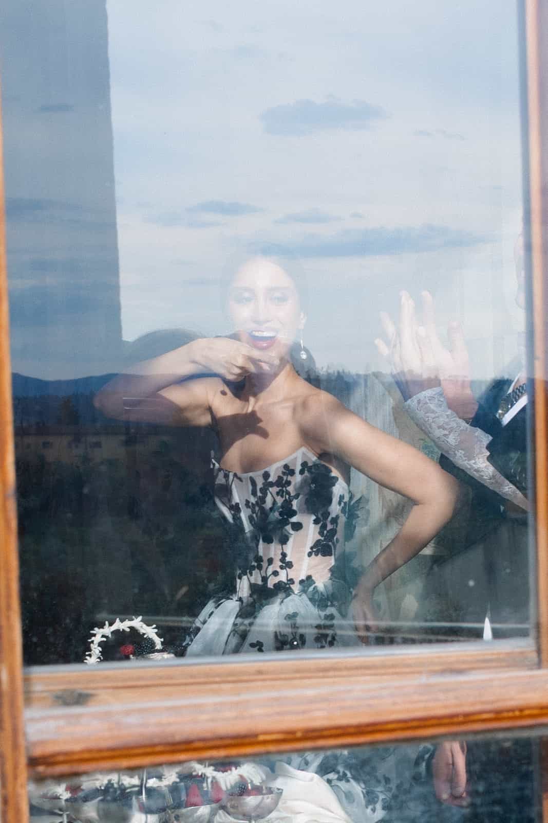 Bride behind glass window with sky reflection, artistic portrait