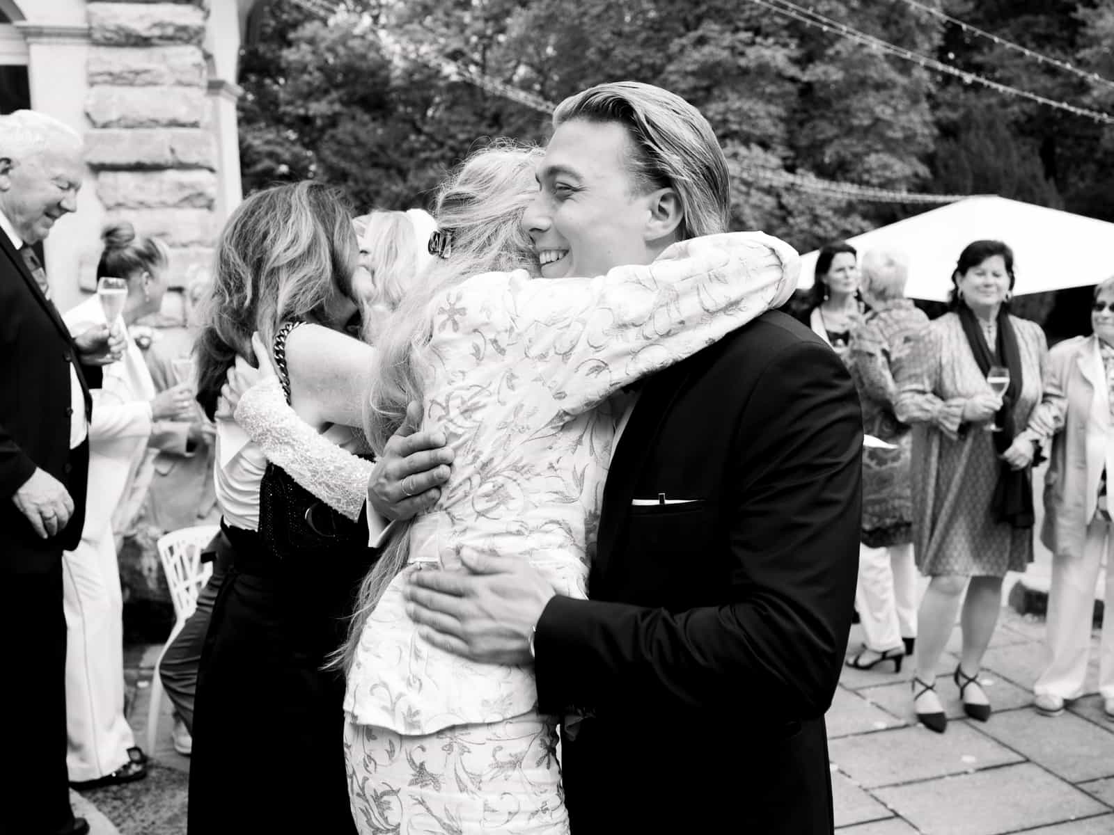 Guest embracing wedding couple after ceremony at Schloss Kartzow in black and white