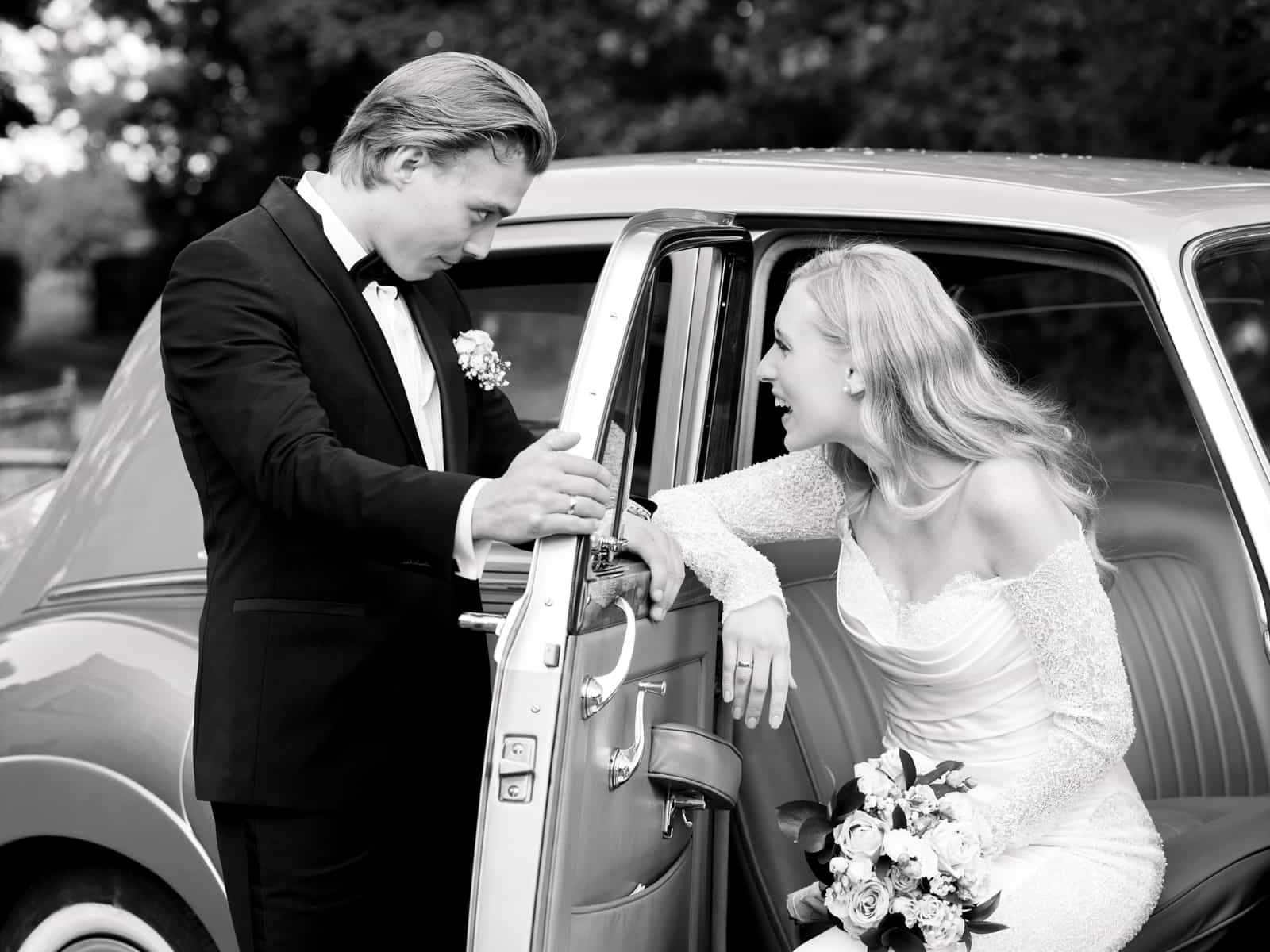 Groom helping bride get into vintage car at Schloss Kartzow castle wedding