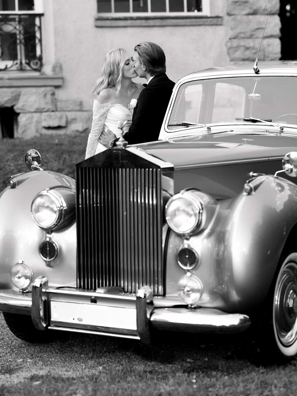 Wedding couple kissing behind Rolls Royce at glamorous Schloss Kartzow castle wedding