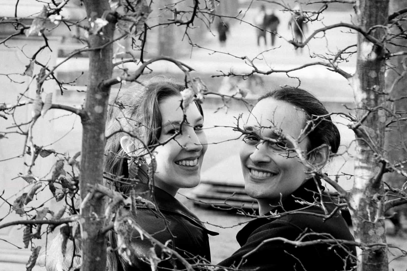 Laughing couple photographed through bare tree branches in winter