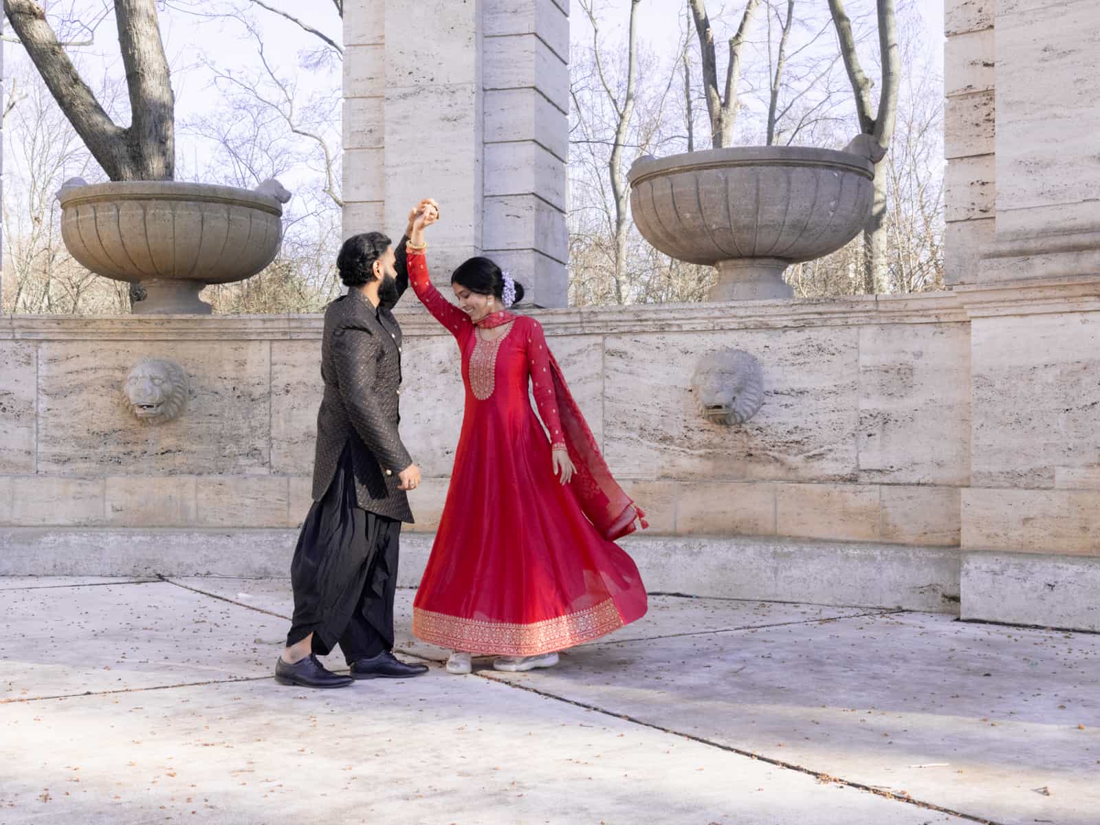 Dancing Indian bridal couple in sweeping movement in front of stone arcades