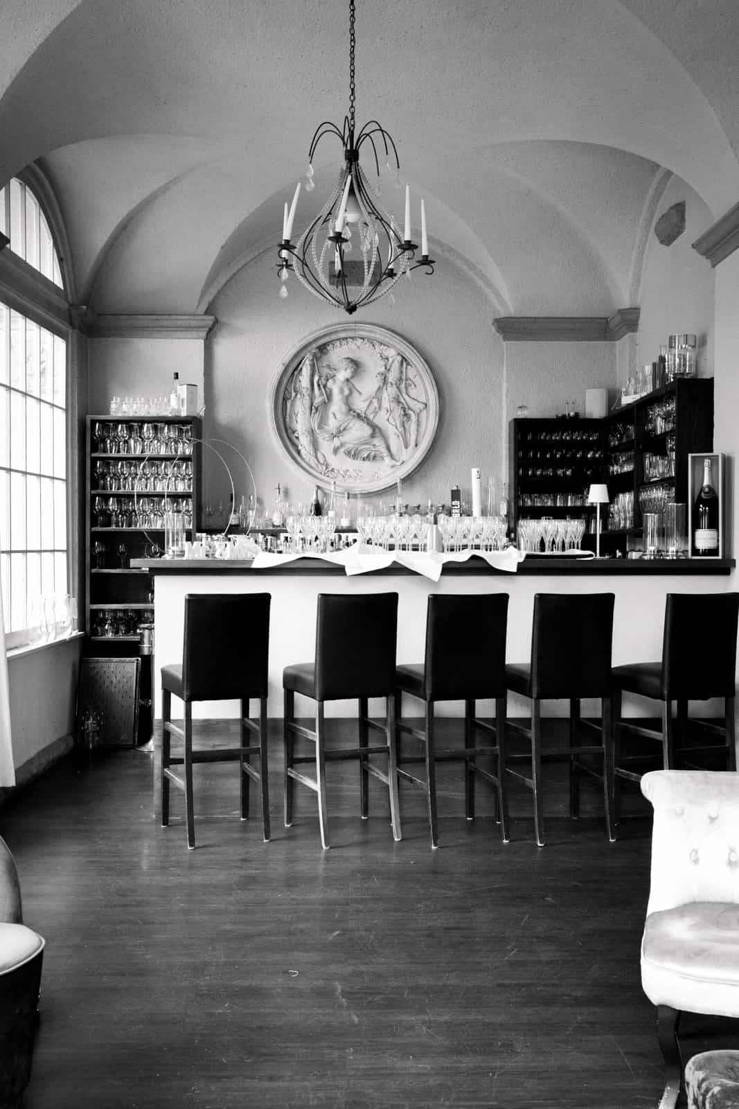 Elegant bar with vaulted ceiling, classical relief and bar stools, black and white