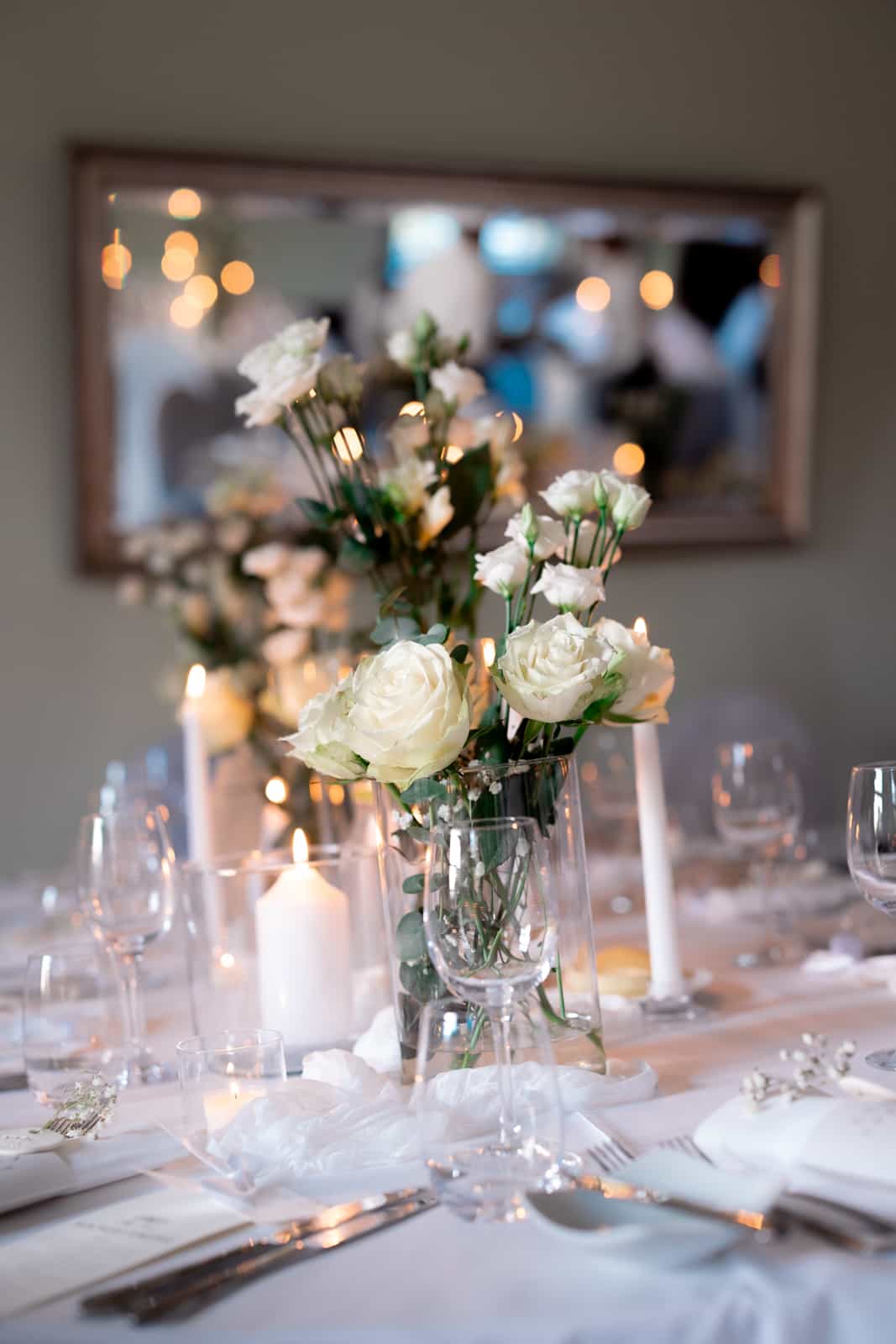 Elegant wedding table decoration with white roses and candles in warm light