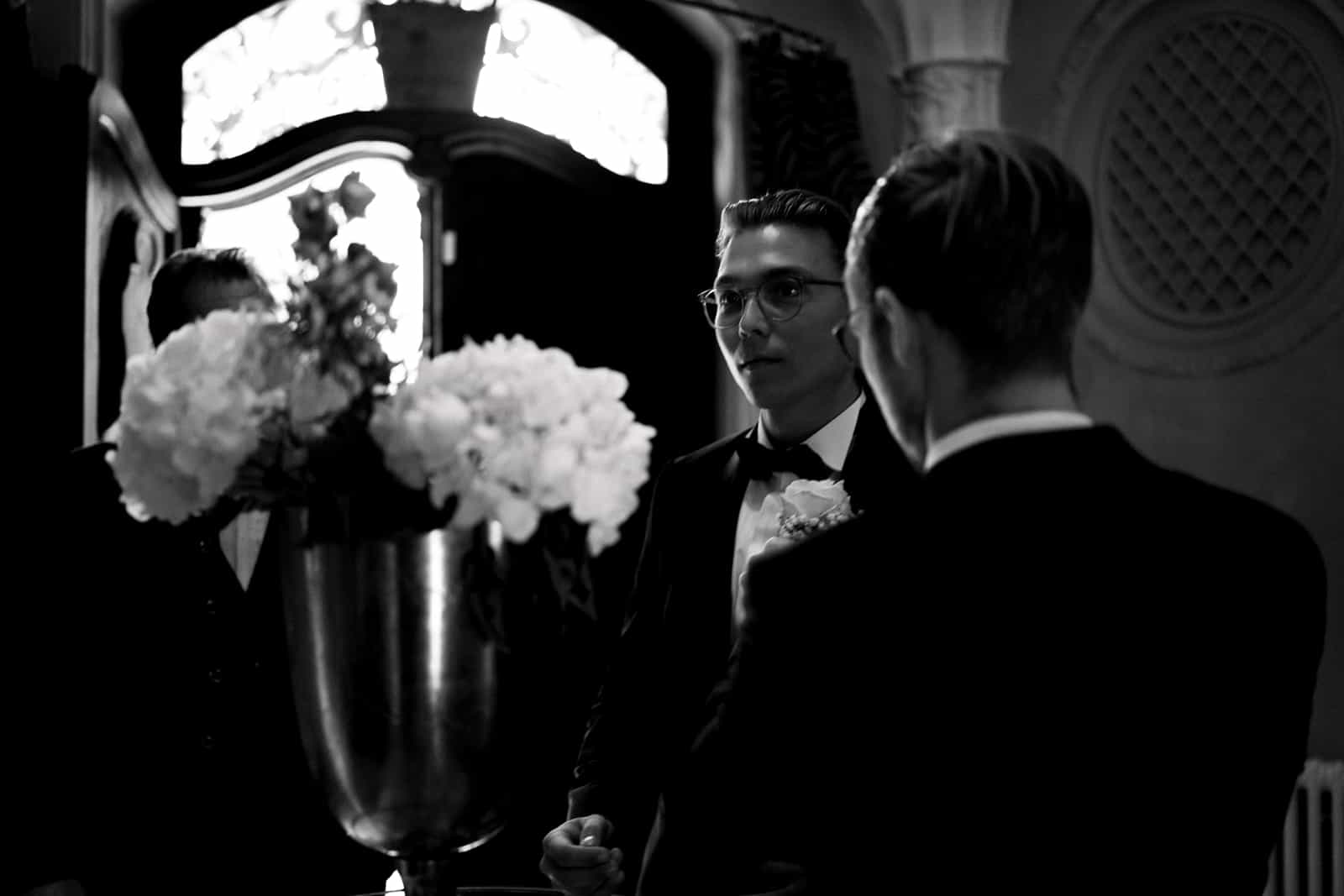 Emotional groom with glasses and boutonniere at wedding ceremony, black and white