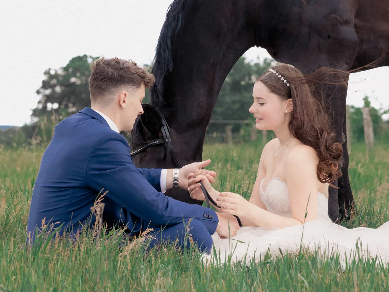 Groom showing bride engagement ring, black horse standing protectively over couple
