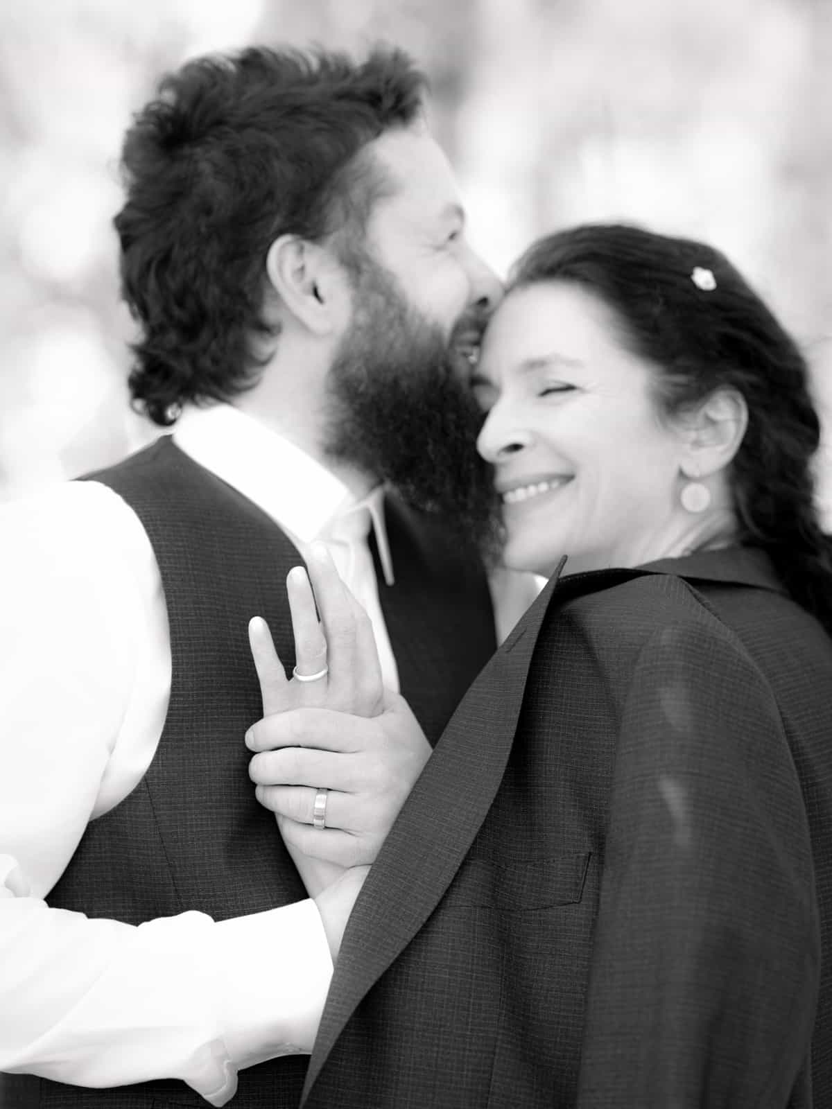 Groom and wedding guest in navy outfits smiling at each other