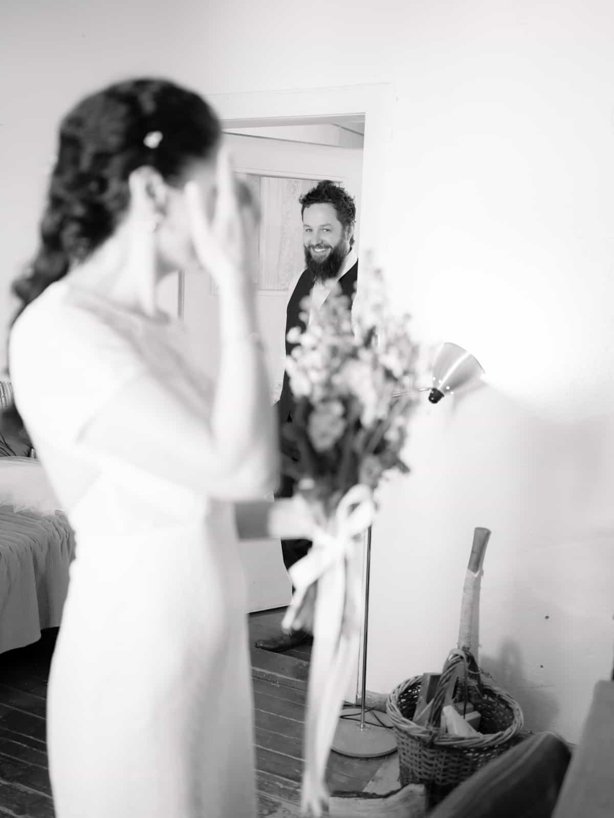 Bride looking over shoulder at smiling groom in doorway