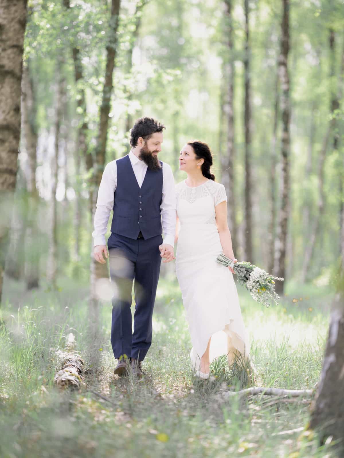 Laughing couple strolling through sunny birch forest