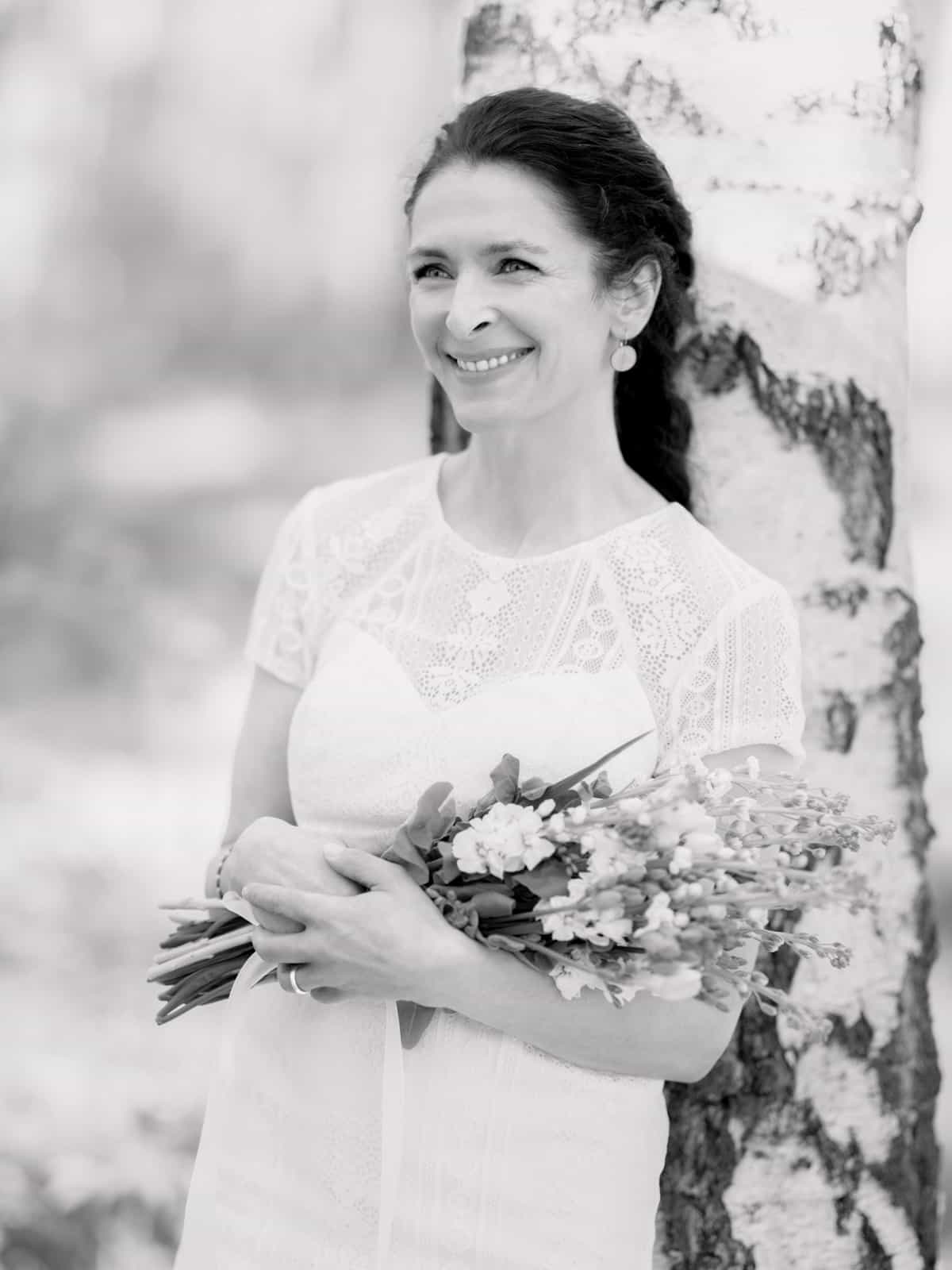 Bridal couple hand in hand in sun-drenched birch forest