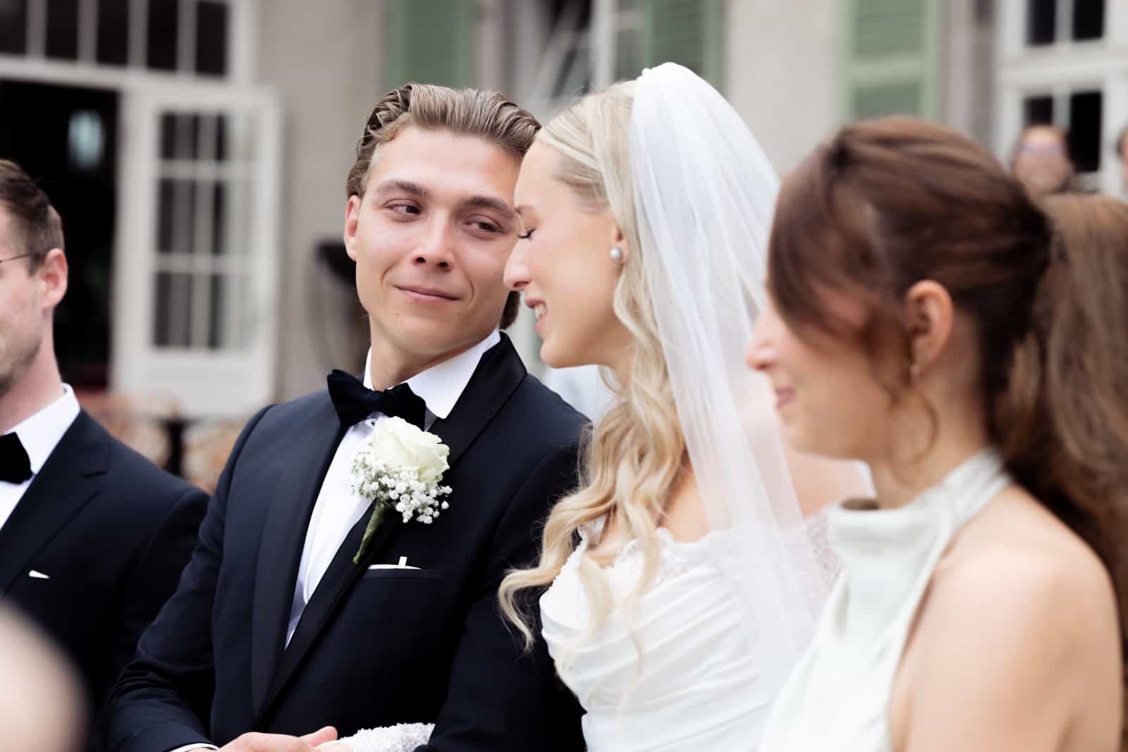 Groom looking lovingly at his veiled bride during the wedding ceremony