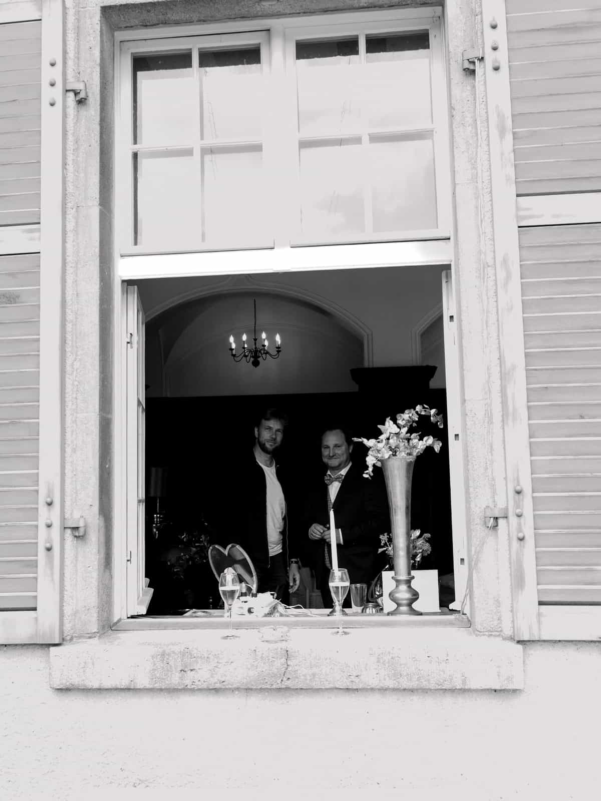Wedding guests at castle window with champagne glasses during reception at Schloss Kartzow