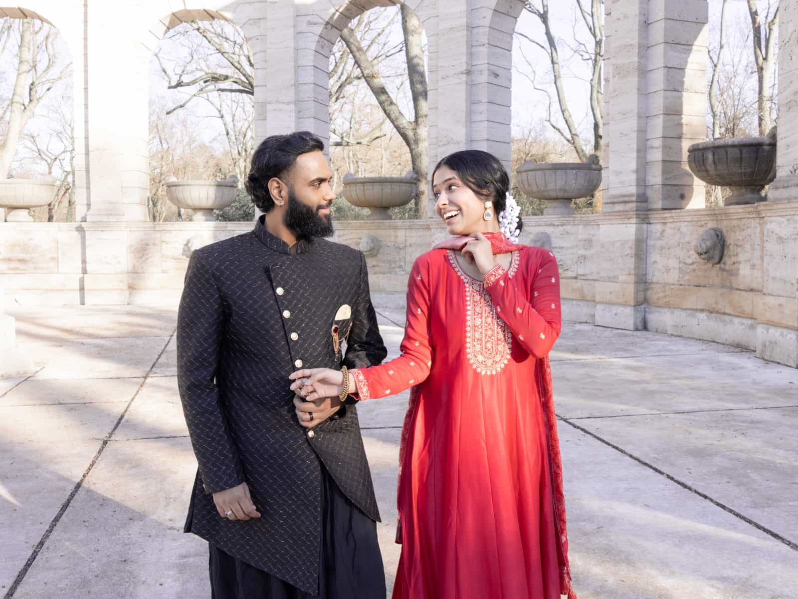 Laughing Indian bridal couple holding hands in joyful moment
