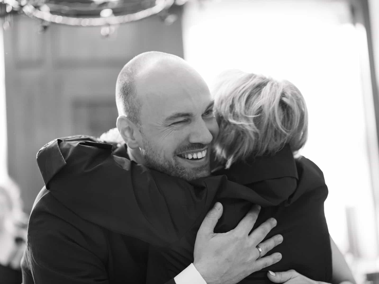 Groom warmly embracing a well-wisher after wedding