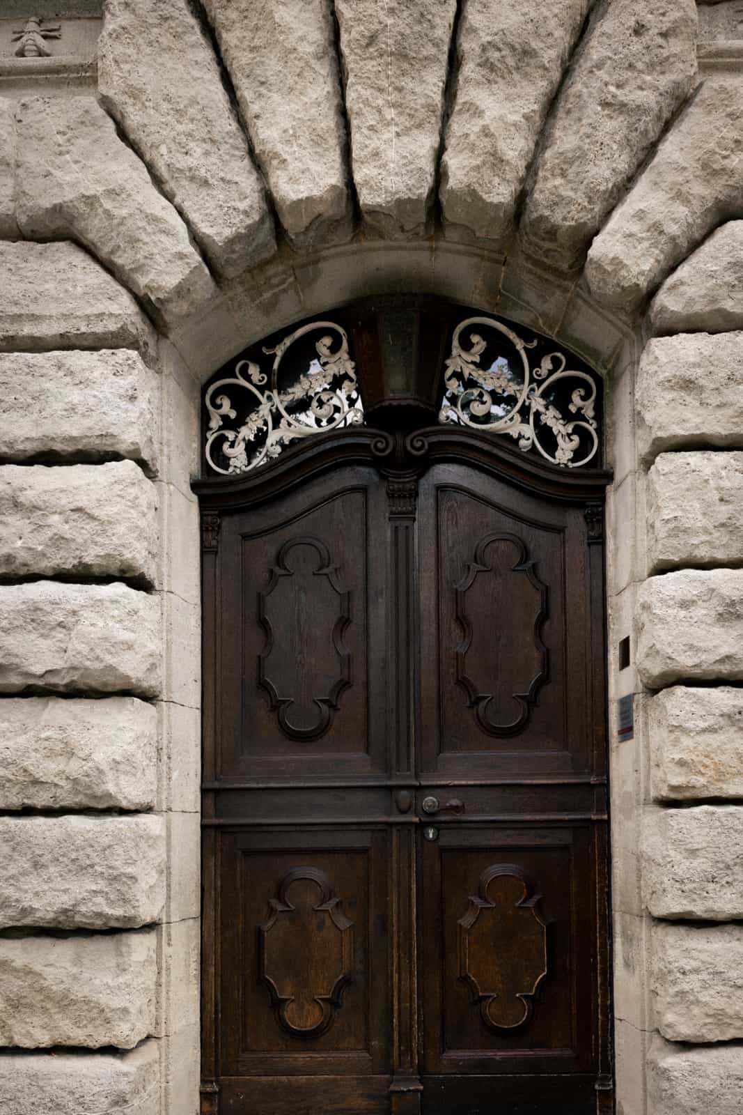 Historic carved wooden door with wrought iron transom in stone archway