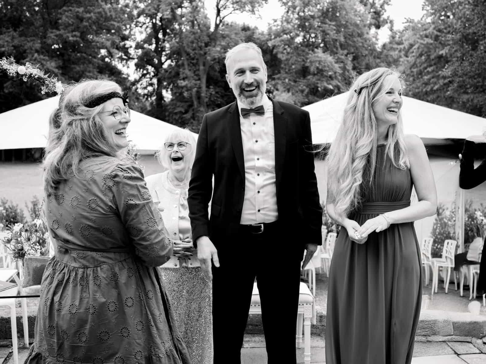 Laughing wedding guests and father of bride at outdoor ceremony Schloss Kartzow