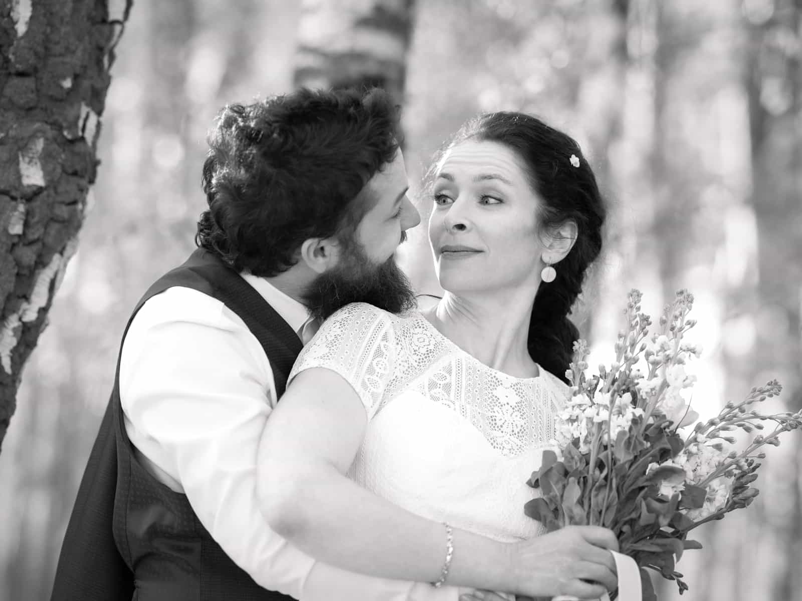 Playful bride making funny face in groom's embrace
