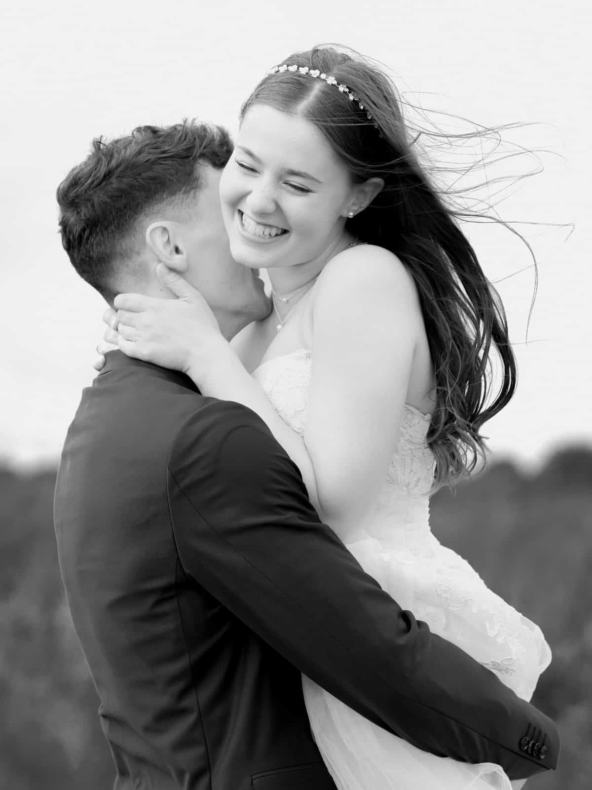 Overjoyed bride with flowing hair embracing groom from behind