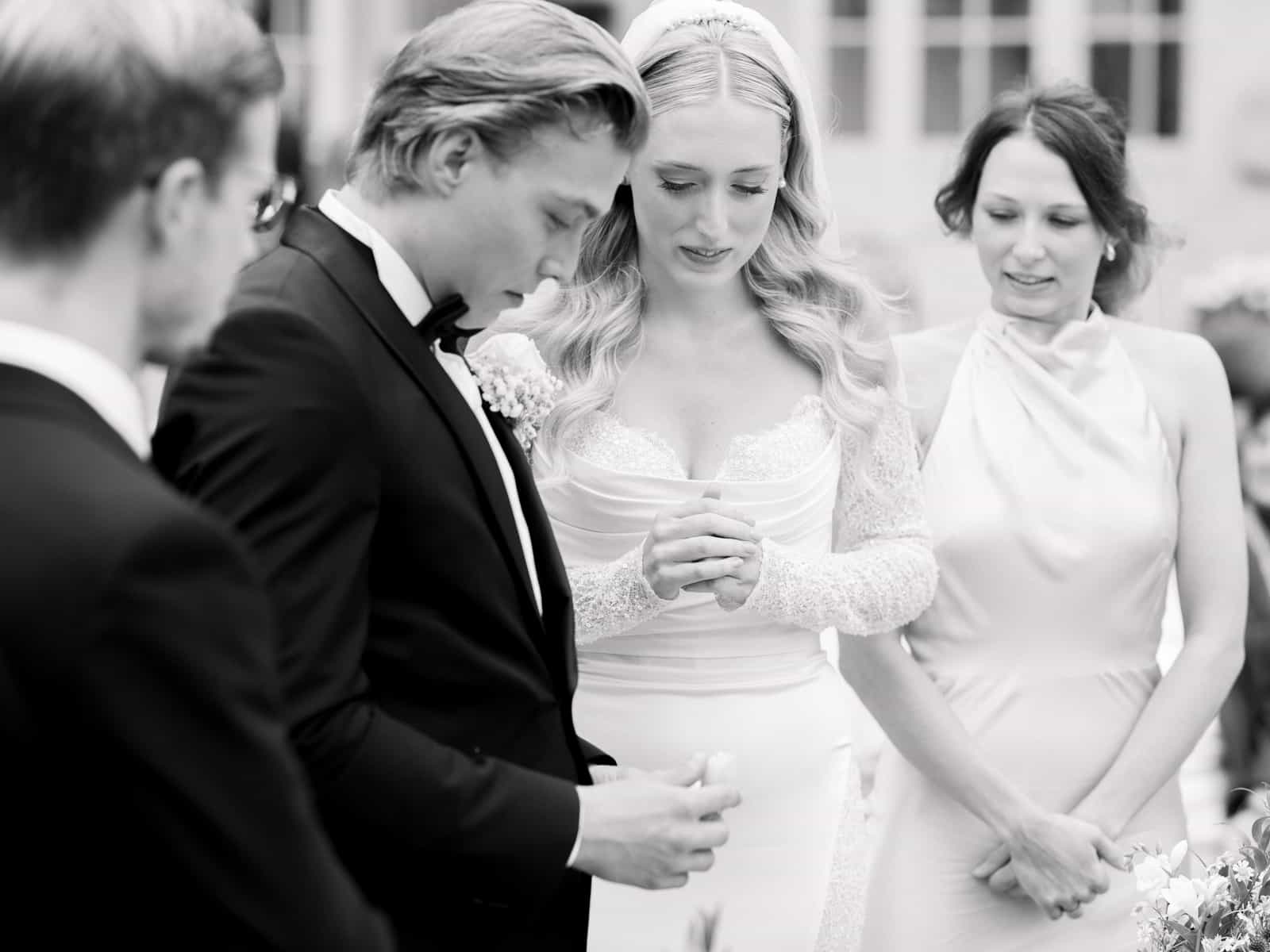 Wedding couple exchanging rings during outdoor ceremony at Schloss Kartzow in black and white