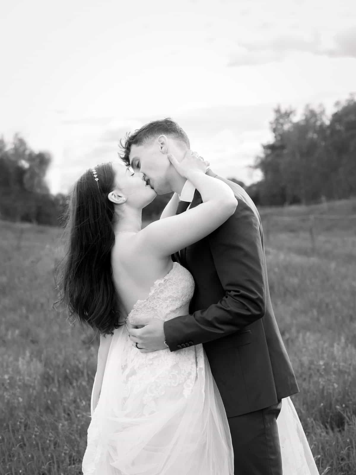 Intimate kiss of couple on field path in classic black and white