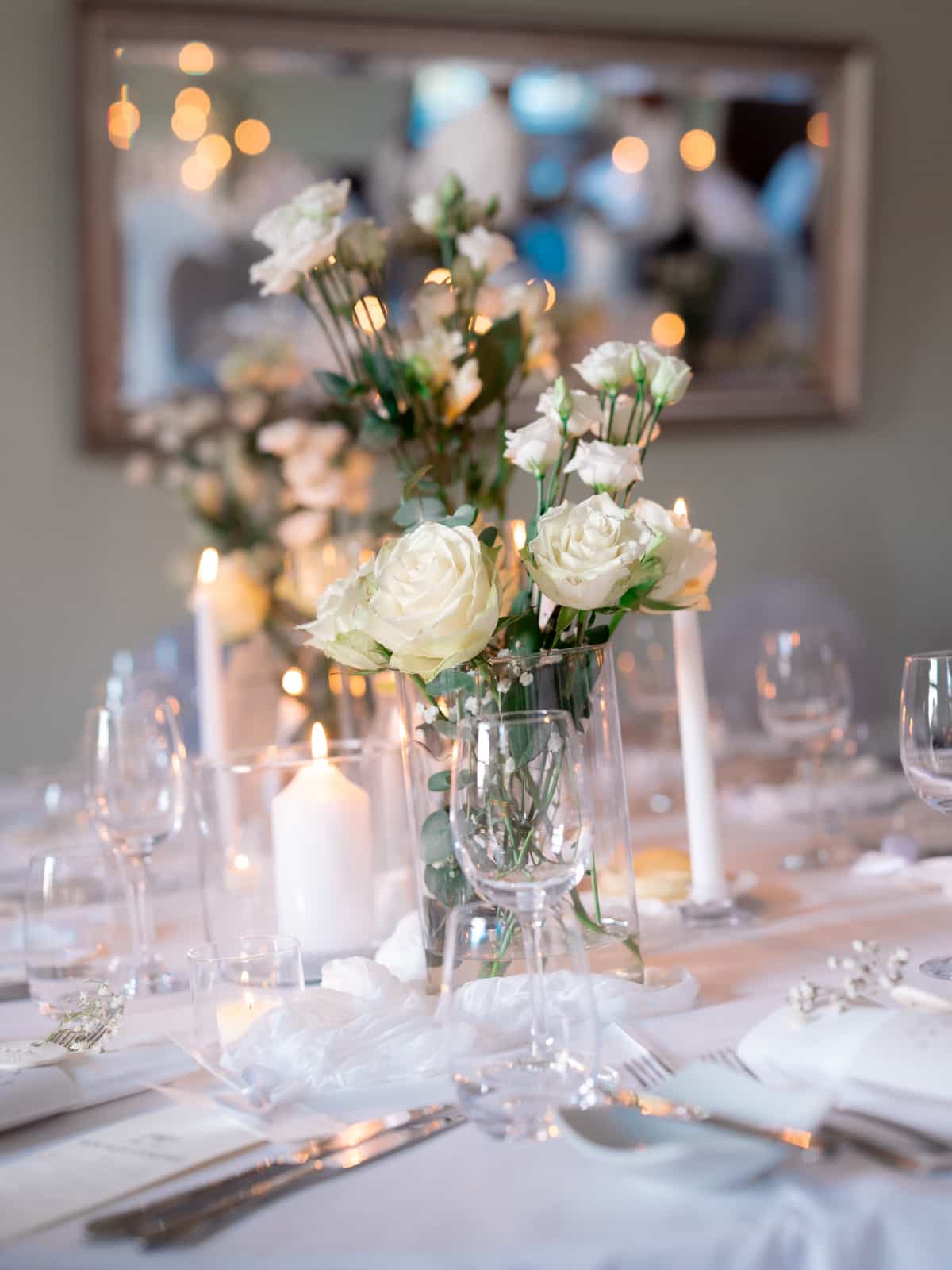 Wedding table with white roses in glass vases and candles - Schloss Kartzow wedding decoration