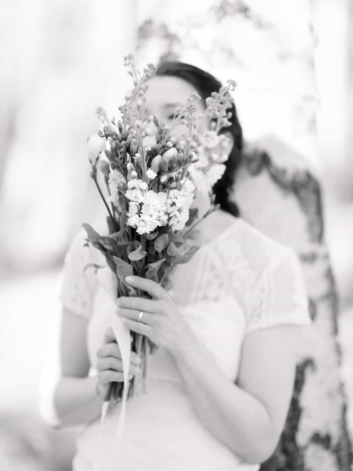 Groom tenderly embracing bride from behind in birch forest