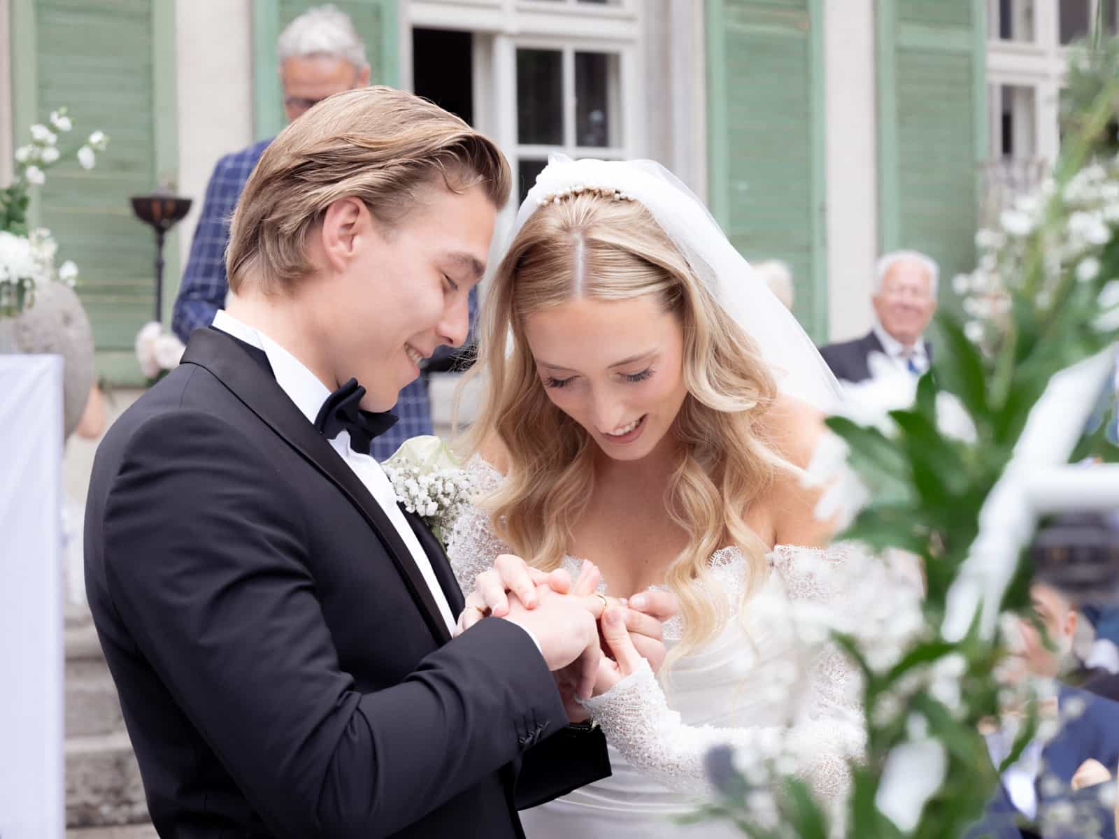 Wedding couple holding hands during ceremony in front of green castle facade at Schloss Kartzow