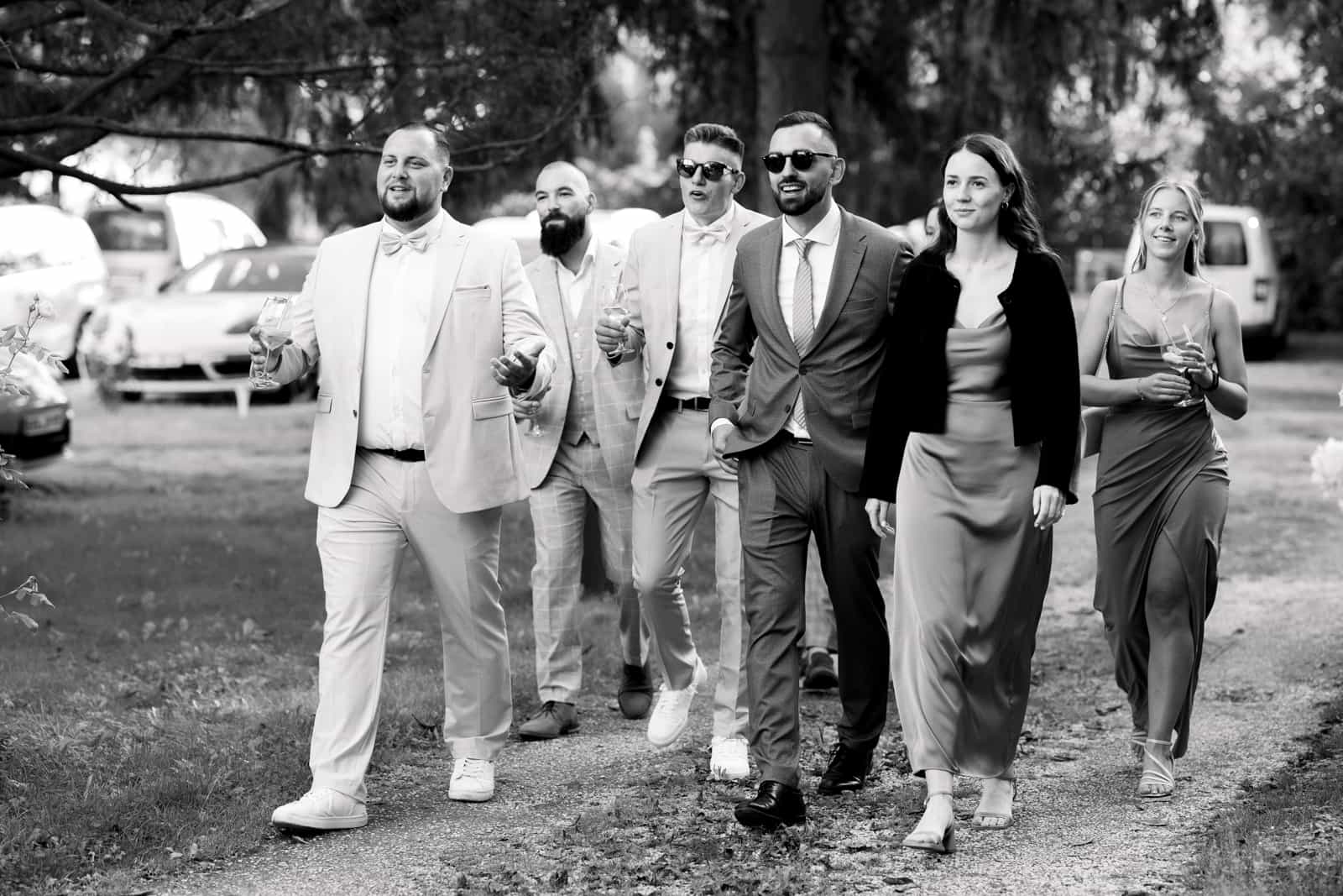 Group of elegantly dressed wedding guests walking together on a path