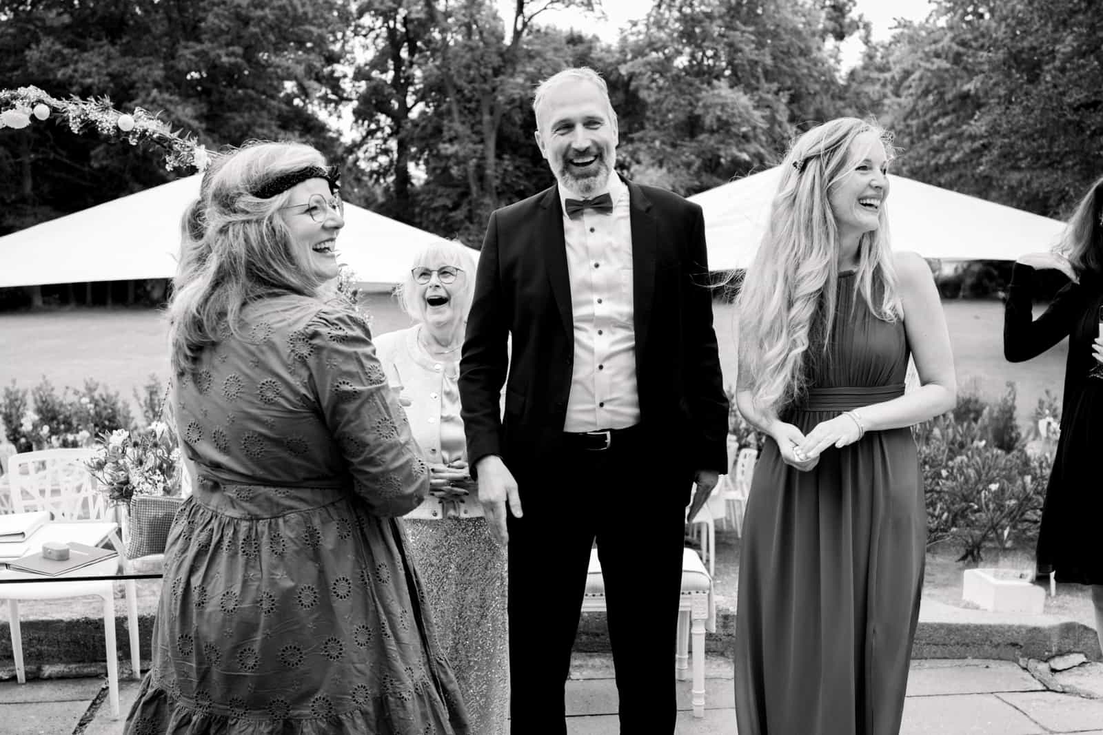 Three wedding guests laughing together in the garden