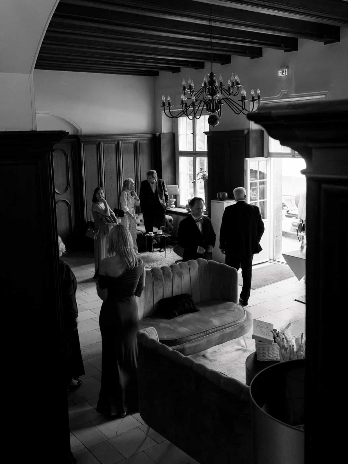 Wedding guests in elegant castle hall with chandelier and antique furniture, wedding photography Schloss Kartzow