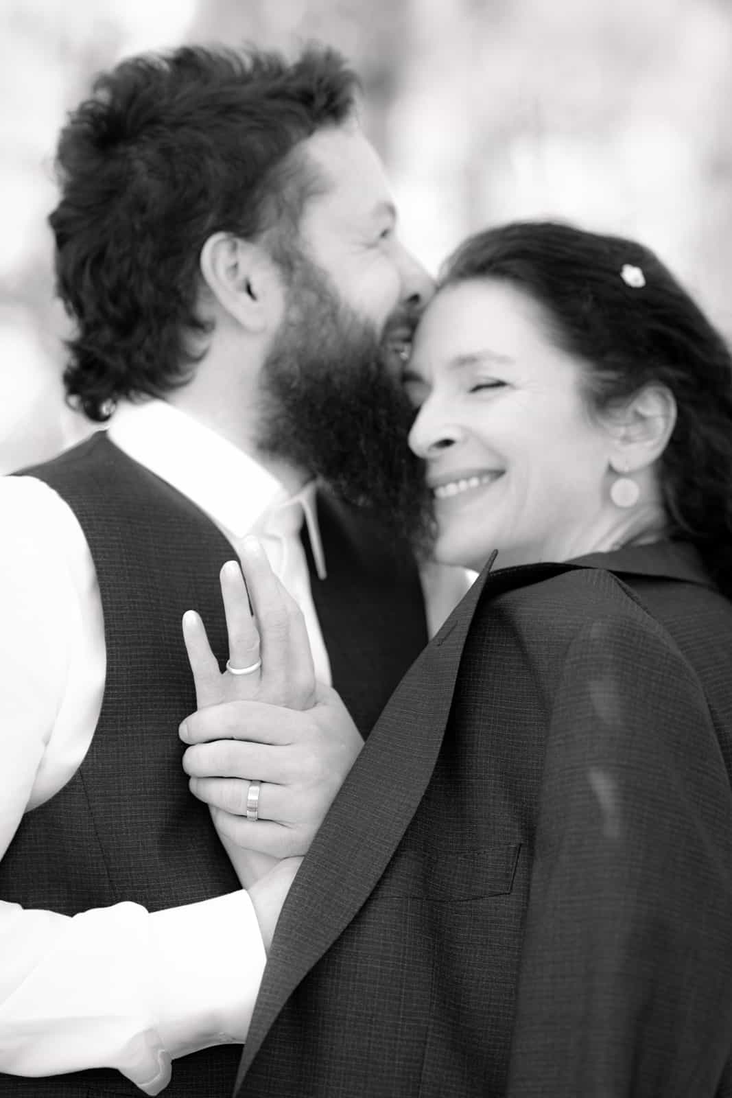 Wedding couple embracing intimately, bride smiling joyfully in black and white wedding photography