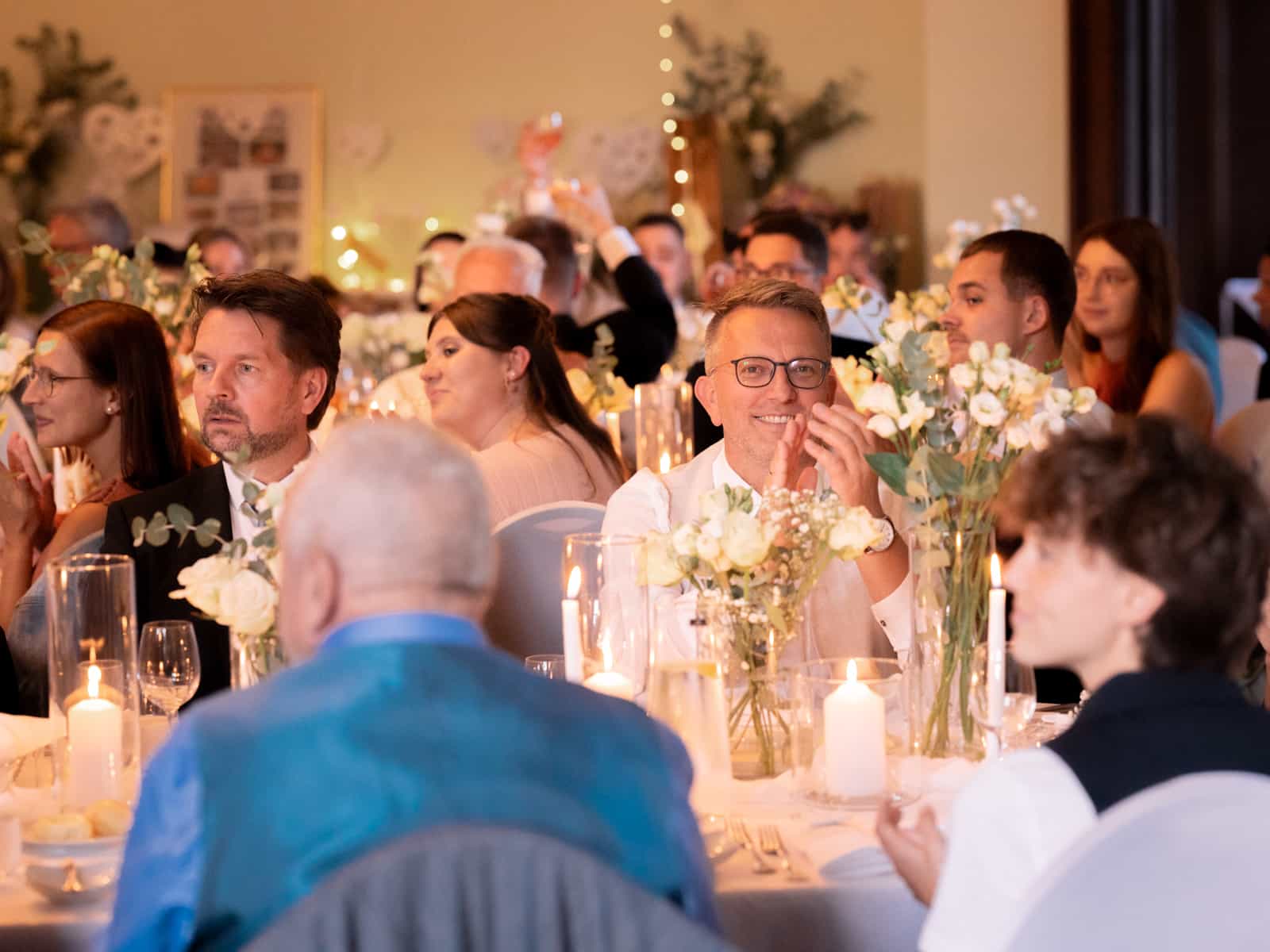 Smiling wedding guests at festively decorated tables with candles - Schloss Kartzow celebration