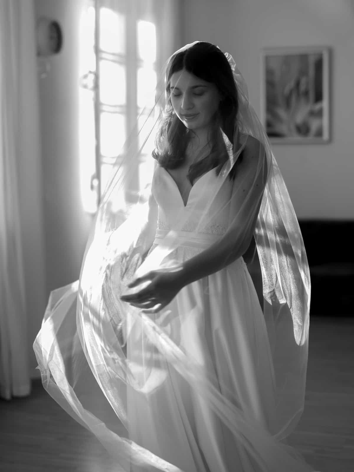Bride in motion with flowing veil in black and white portrait