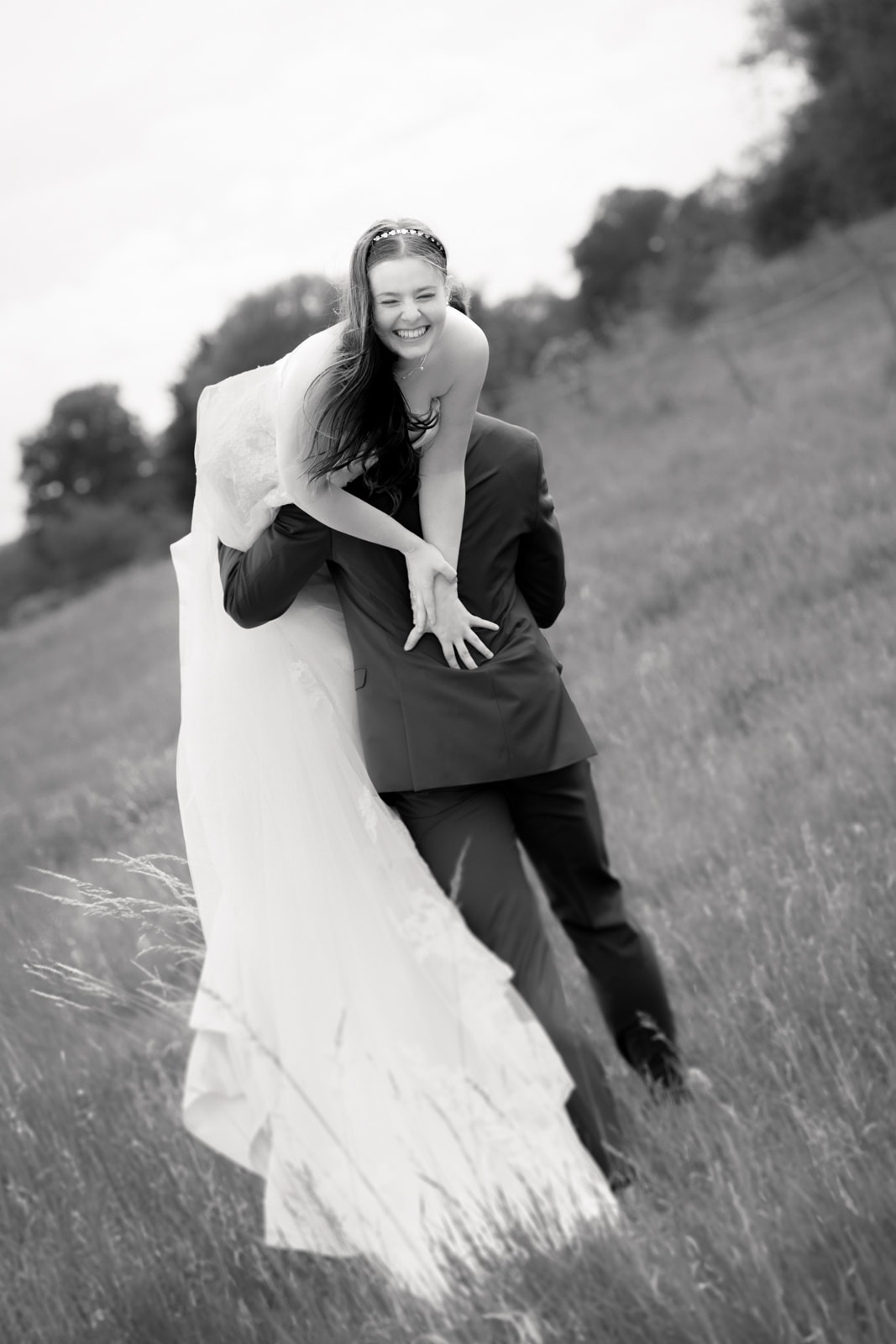 Lachendes Brautpaar in Bewegung auf Feld bei Hochzeit