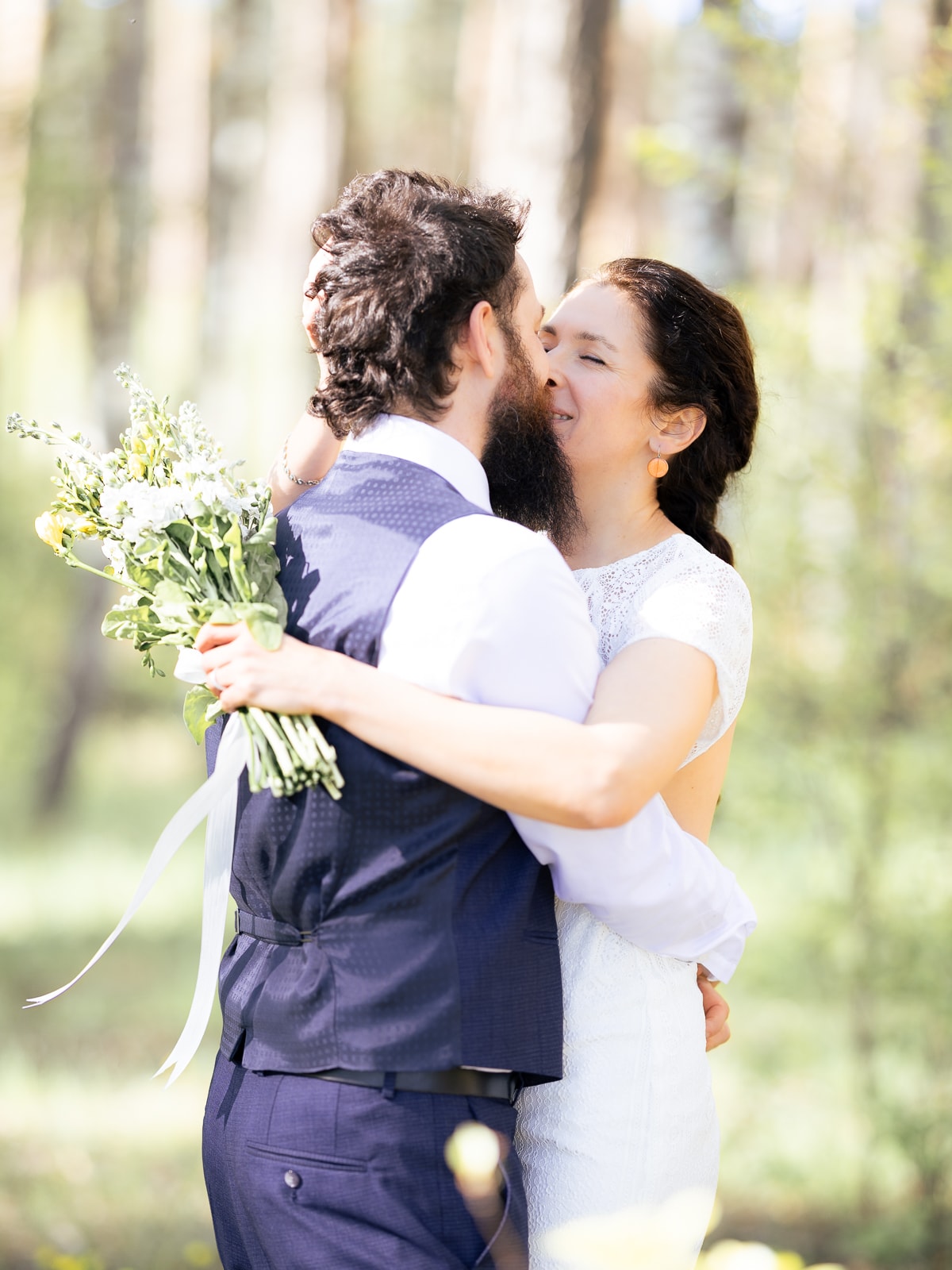 Braut hält wilden Brautstrauß mit weißen und gelben Blumen