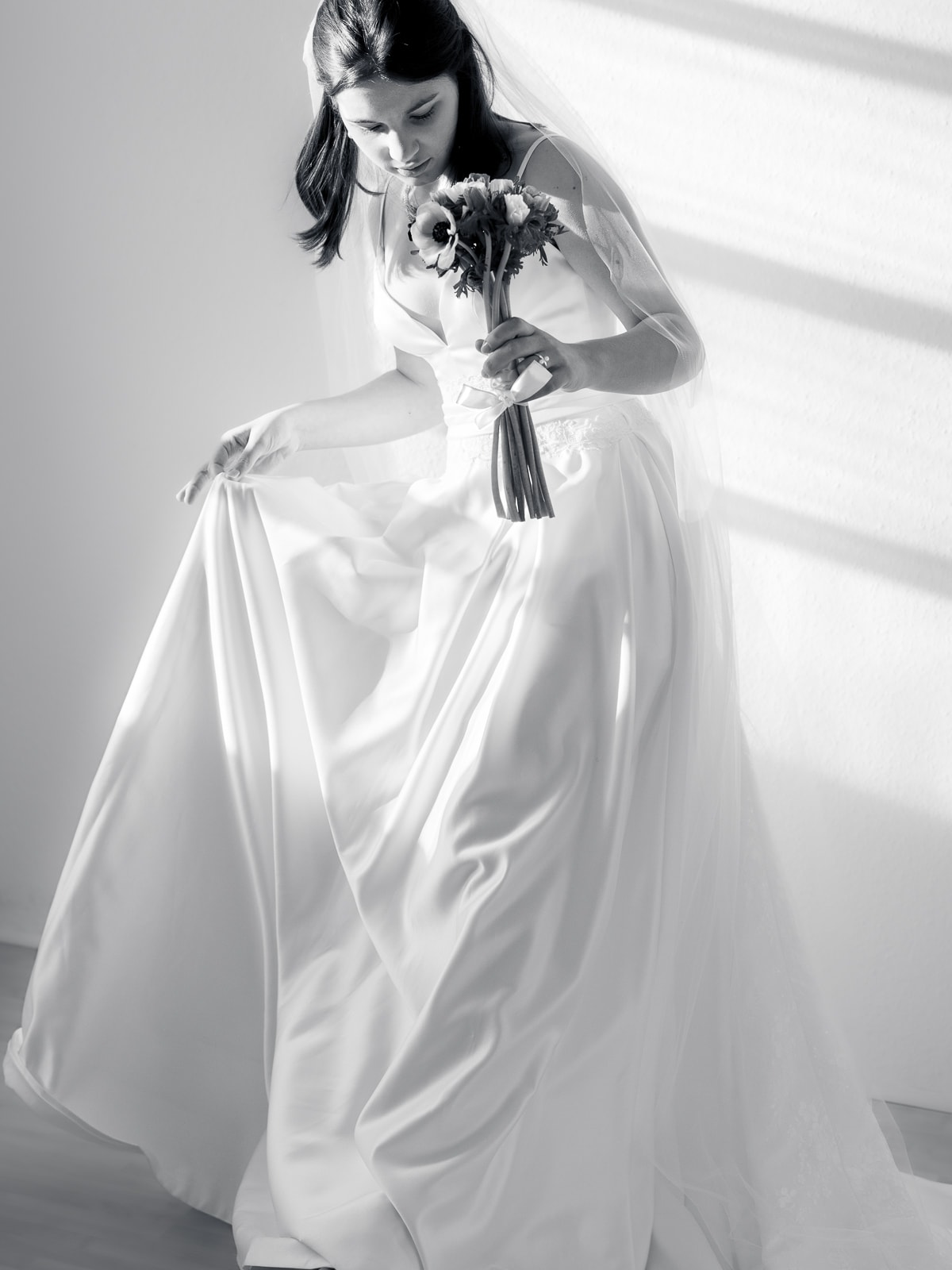 Schwarz-Weiß Portrait einer Braut mit fließendem Kleid und Blumenstrauß