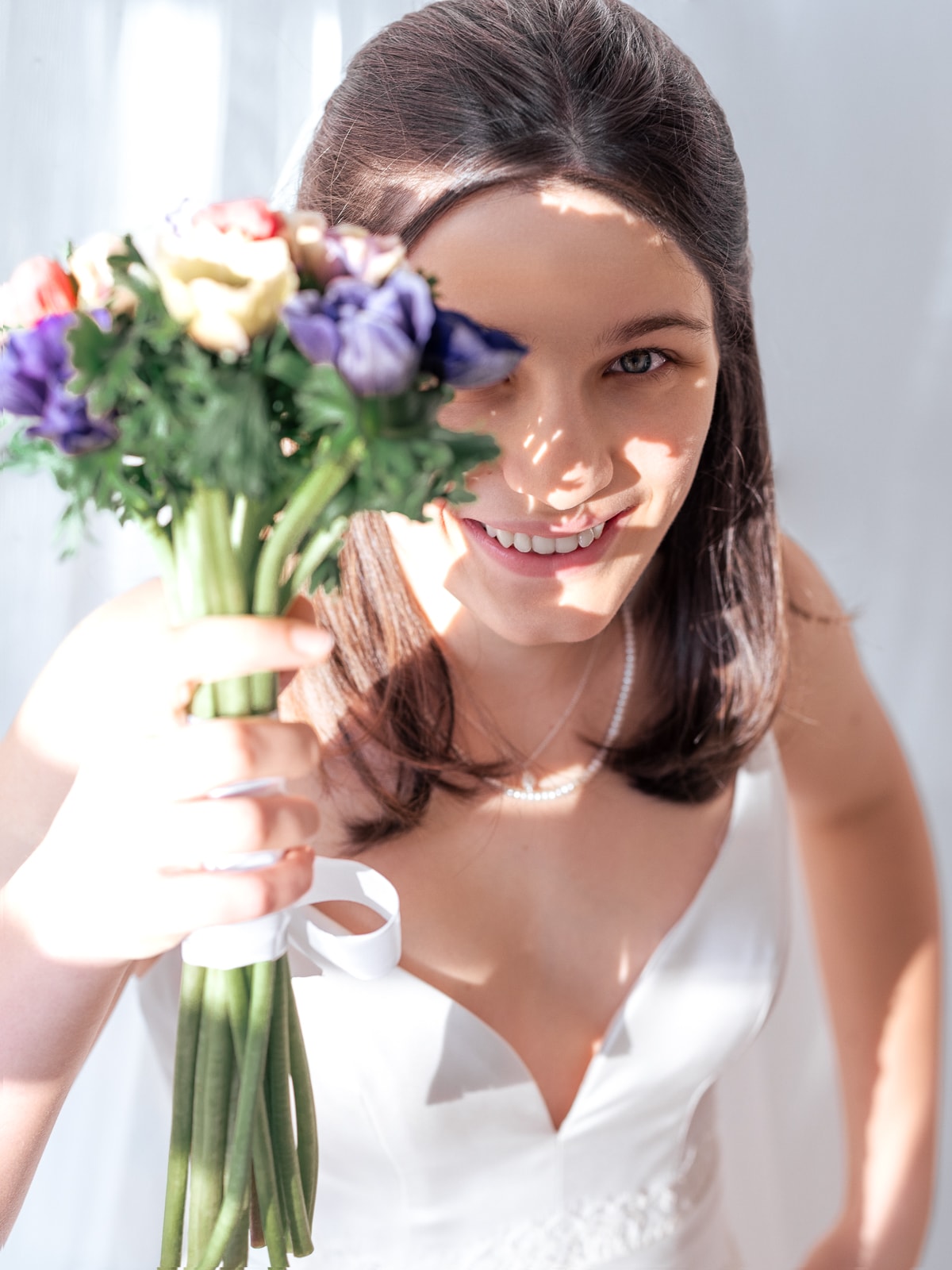 Glückliche Braut mit buntem Wildblumenstrauß und strahlendem Lächeln
