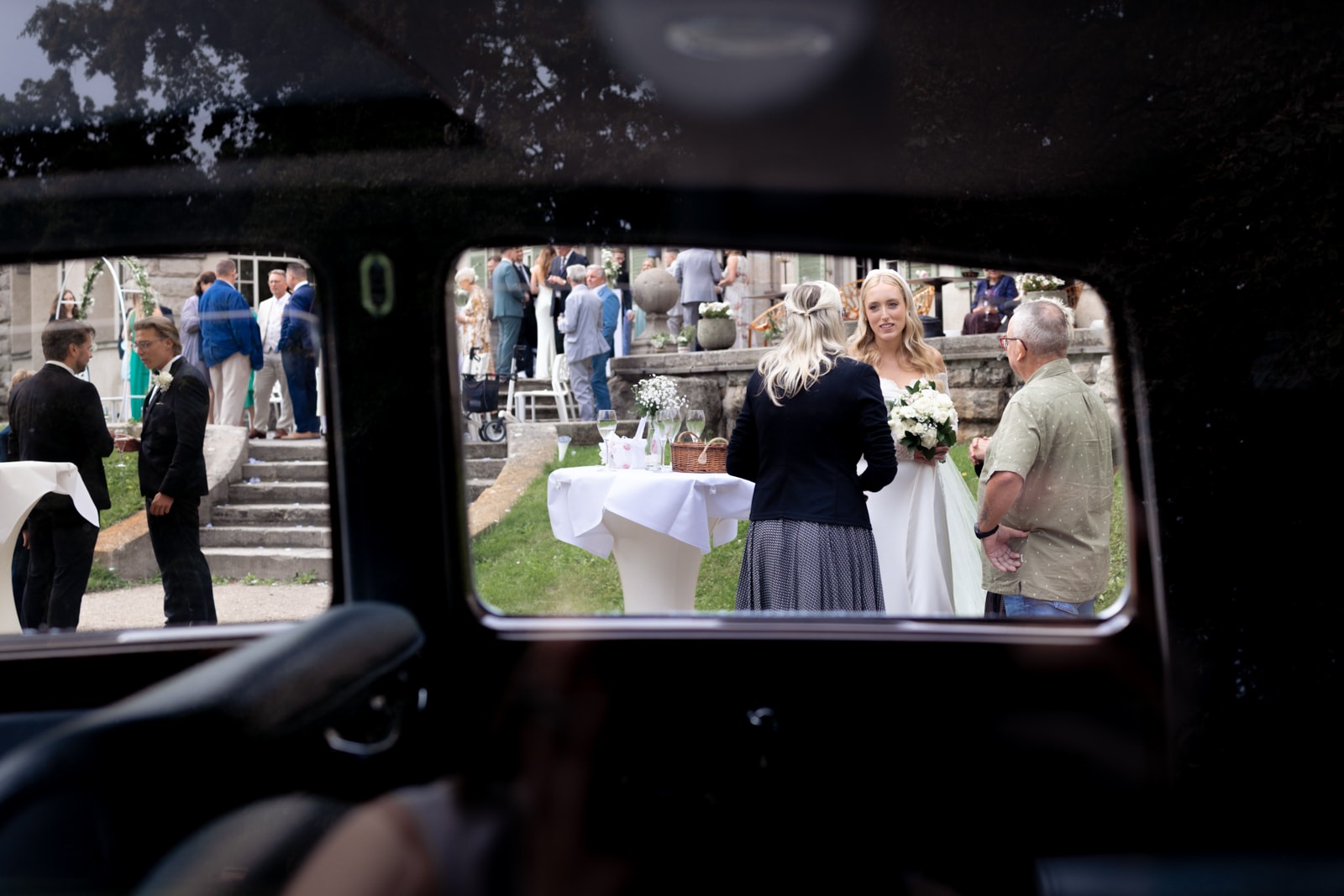 Blick durch Oldtimer-Fenster auf Braut bei Hochzeitsempfang