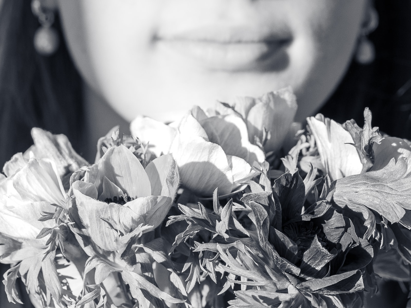 Detail shot of smiling bride with anemone bouquet in black and white