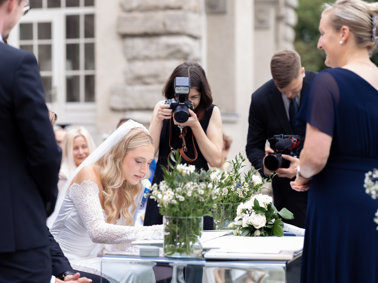 Bride signing wedding documents at Schloss Kartzow with photographers in background
