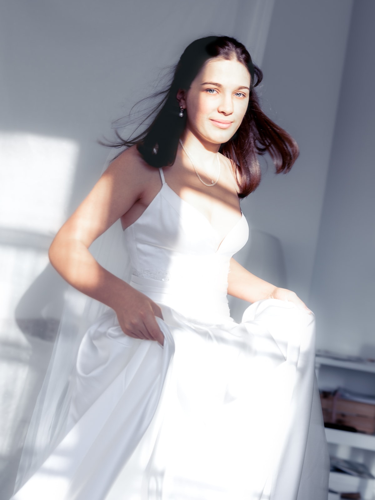 Smiling bride in sunlight with pearl earrings and white gloves